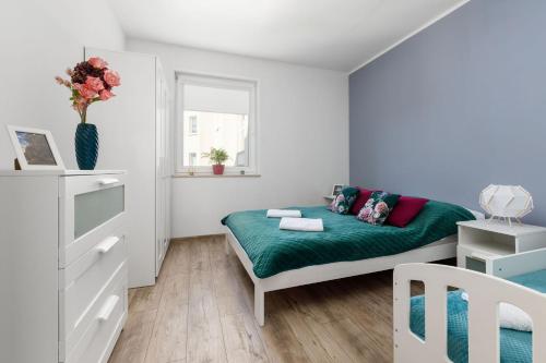 niewielka sypialnia z łóżkiem z zielonym kocem w obiekcie Przestronny apartament Centrum między 2 jeziorami w Olsztynie