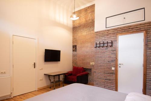 a bedroom with a brick wall and a red chair at Apartment in old TBILISI in Tbilisi City