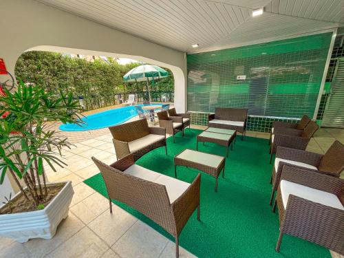 a patio with a pool and chairs and a swimming pool at Hotel Nacional Inn Guarujá in Guarujá