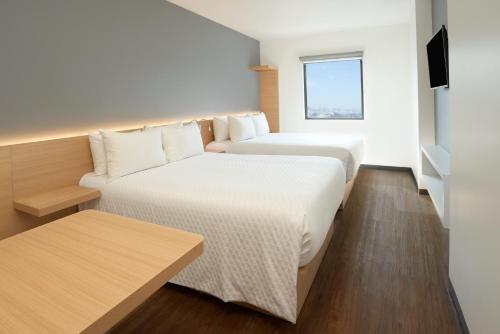 a hotel room with two beds and a window at GAMMA Querétaro in Querétaro