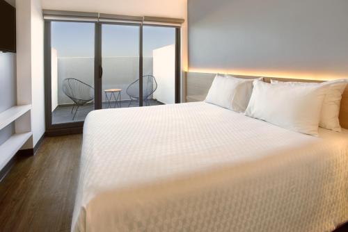 um quarto com uma grande cama branca e uma varanda em GAMMA Querétaro em Querétaro