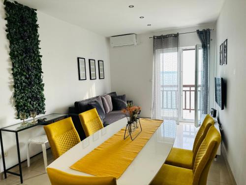 - un salon avec une table et des chaises jaunes dans l'établissement Apartmani Mutogras, à Podstrana