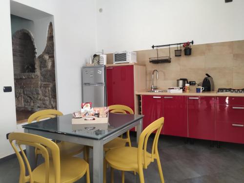 Una cocina con sillas amarillas, una mesa y armarios rojos. en Vicolo degli Osci, en Caserta