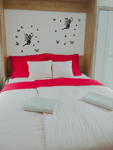 uma cama com lençóis vermelhos e brancos e borboletas na parede em Nika 2 em Rijeka