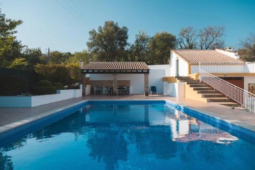 a swimming pool in front of a house at Casa das Palmeiras - Villa com piscina, BBQ e ar condicionado in Albufeira
