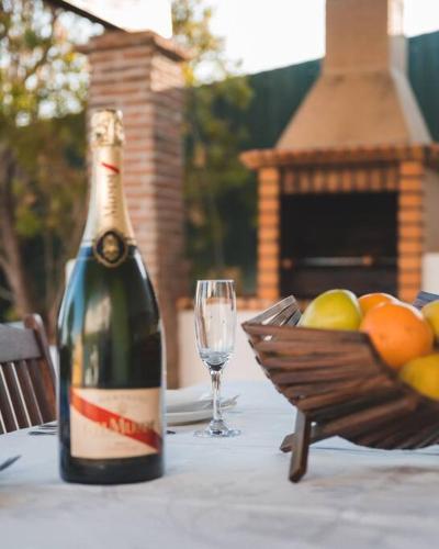 a bottle of wine sitting on a table with a glass at Casa das Palmeiras - Villa com piscina, BBQ e ar condicionado in Albufeira
