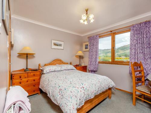 a bedroom with a bed and a chair and a window at Riverfoot in Glenelg