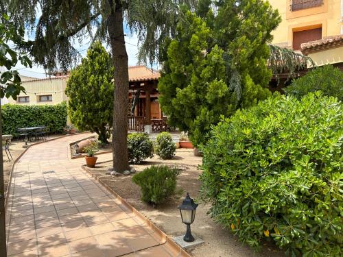 a garden with a sidewalk and trees and a building at Hotel El Castrejon in Cebreros
