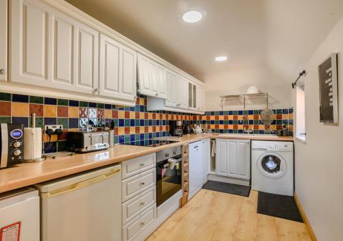 a kitchen with white cabinets and a washer and dryer at Chestnut Barn 