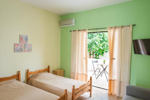 a bedroom with two beds and a sliding glass door at ARISTOTELIS Apartments in Vathí