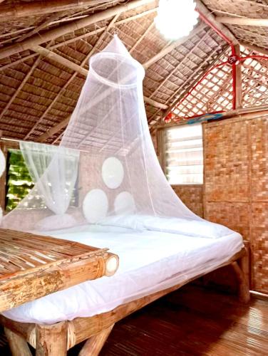 a bed in a thatched room with a net at La Maison Guesthouse in Manlocahoc
