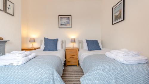 Duas camas individuais num quarto com lençóis azuis e brancos em Ivy Dene em Crich
