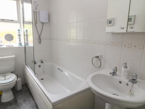 a white bathroom with a toilet and a tub and a sink at 1 Old Farm Court in Barnstaple