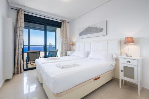 ベニドルムにあるGemelos 26 Resort Apartment 27C Levante Beachの白いベッドルーム(ベッド1台、バルコニー付)