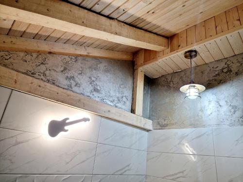 a bathroom with a shower with a shadow of a guitar on the wall at Vila N&N Palace in Bistriţa Bîrgăului