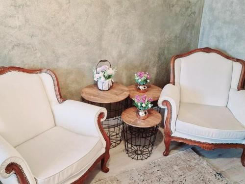 twee witte stoelen en een tafel met bloemen erop bij Vila N&N Palace in Bistriţa Bîrgăului