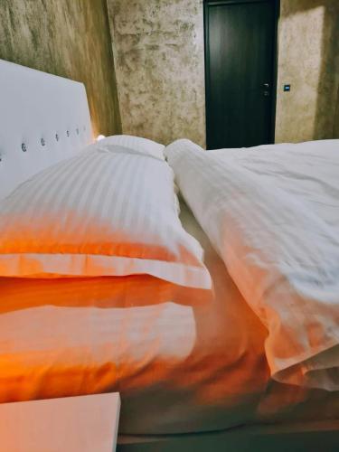 a bedroom with a bed with white and orange pillows at Vila N&N Palace in Bistriţa Bîrgăului