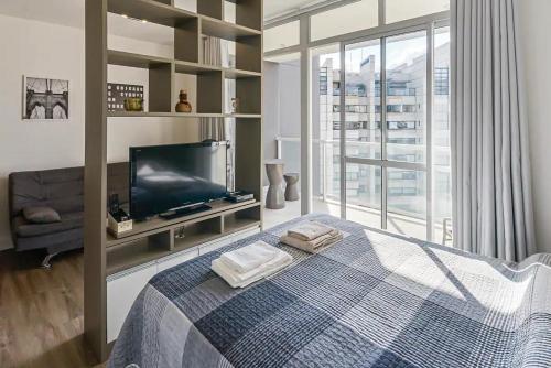 a bedroom with a bed and a tv and a window at Flat Completo na Ponte Estaiada SP in Sao Paulo