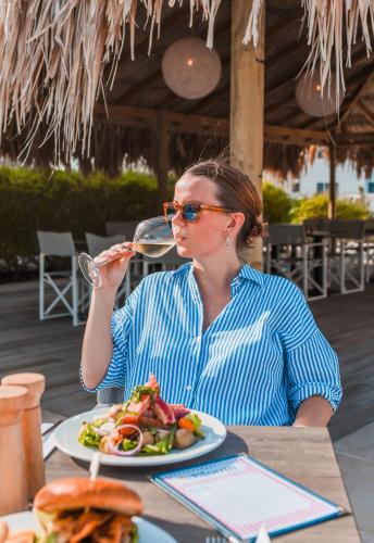 a woman sitting at a table drinking a glass of wine at Grand Windsock Bonaire in Kralendijk