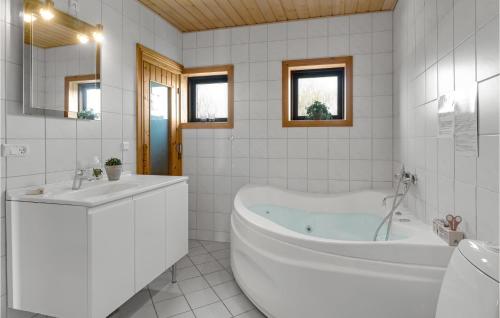 La salle de bains blanche est pourvue d'une baignoire et d'un lavabo. dans l'établissement Amazing Home In Glesborg With 5 Bedrooms, Sauna And Wifi, à Tvedhuse