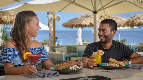 a man and a woman sitting at a table eating food at Grand Windsock Bonaire in Kralendijk