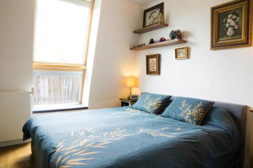 um quarto com uma cama com lençóis azuis e uma janela em Beautiful Rooftop between Paris and Versailles em Chaville