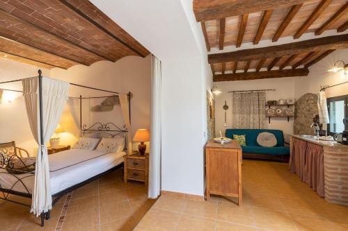 um quarto com uma cama de dossel e um sofá azul em Casale Rosmarino em Suvereto