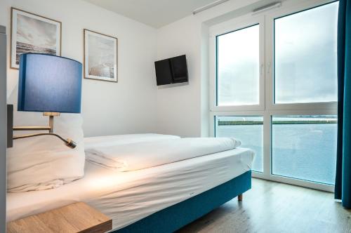 ein Schlafzimmer mit einem Bett mit einer Lampe und einem Fenster in der Unterkunft Residenz Bollwark 312 in Kappeln