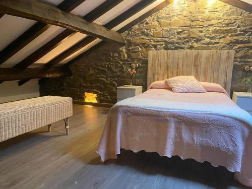 a bedroom with a bed and a stone wall at POSADA de BUSTIELLO in Mieres
