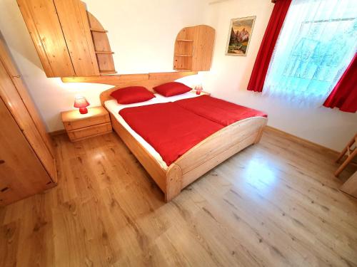 a bedroom with a large wooden bed with red sheets at Apartmaji Zupanc Ivanka in Bohinj