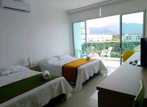 a bedroom with two beds and a large window at * * Magnífico * * apto en la playa * *Costazul 405 in Santa Marta