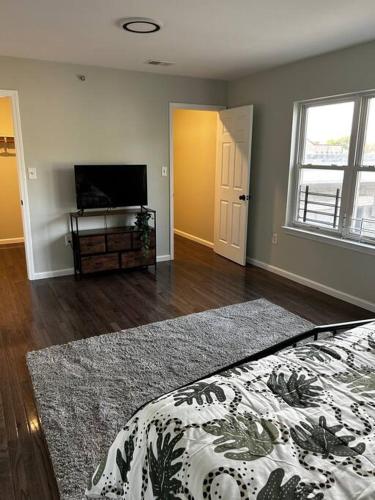 a living room with a bed and a television at Spacious Master Bedroom in Newark