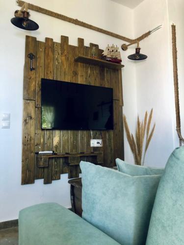 a living room with a wooden wall with a tv at Vlami's House Andros in Apróvaton
