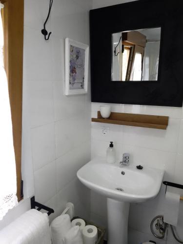 uma casa de banho branca com um lavatório e um espelho em El Rinconin de Degu em San Juan de Parres