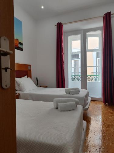 a hotel room with three beds and a window at Guest House Rooms in Bairro Alto in Lisbon