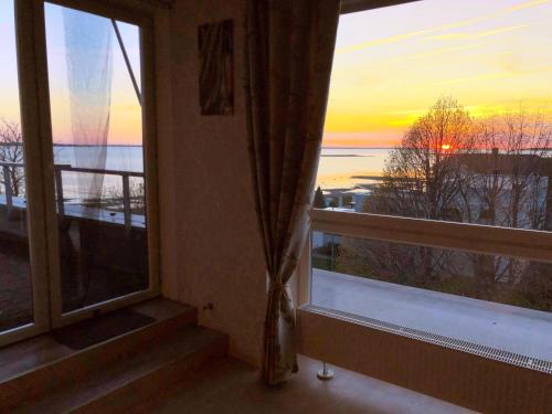 um quarto com uma janela com vista para o pôr-do-sol em Sunset Dream Apartment with a panoramic seaview em Haapsalu
