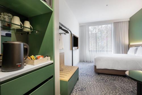 Holiday Inn Dandenong, an IHG Hotel في داندينونج: غرفة فندقية بسرير وغرفة بسرير ومطبخ
