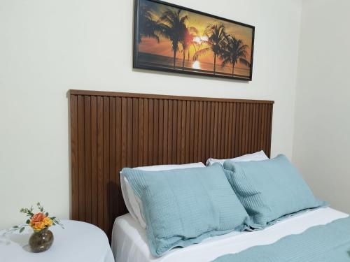 a bed with a wooden headboard and two blue pillows at Casa da Tetê in Fernando de Noronha