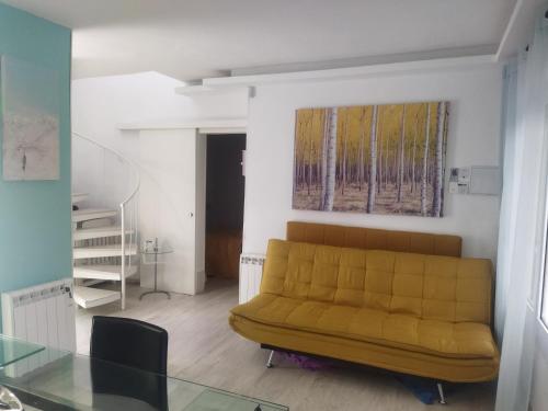a living room with a yellow couch and a glass table at Casita playa in Calafell