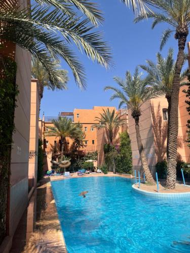una piscina con palmeras en un complejo en Riad Palmeraie en Marrakech