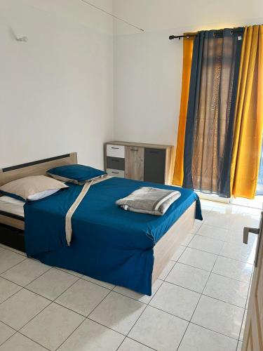 Montjoly的住宿－Maison des Coulicous - 1 à 2 chambres，一间卧室配有蓝色的床和黄色窗帘