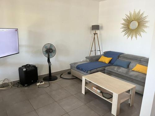uma sala de estar com um sofá e uma mesa em Maison des Coulicous - 1 à 2 chambres em Montjoly