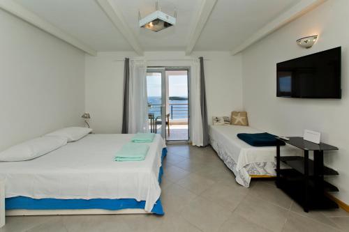 a bedroom with two beds and a television and a balcony at Rino in Hvar