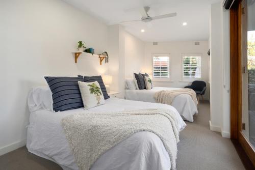 two beds in a room with white walls at Beach Retreat in Sydney