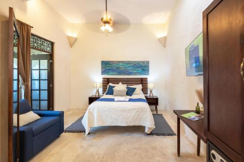 een slaapkamer met een bed en een blauwe bank bij Casa Dos Lirios Hotel Boutique in Mérida