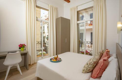 a bedroom with a bed and a desk and windows at Antonios Hostal in Sitges