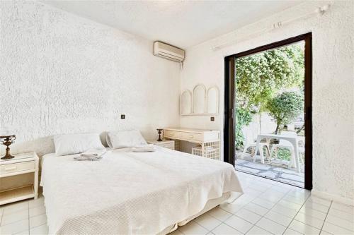 a white bedroom with a bed and a large window at Nemesis House Elani Beach in Elani