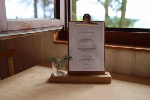 Aussichtsreich Odenwald في فالد-ميشيلباخ: وضع لافتة على طاولة مع مزهرية