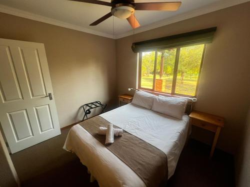 a bedroom with a bed with a ceiling fan and a window at 3-Bedroom House, Greenway Woods, White River in White River