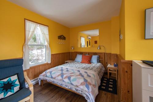 a bedroom with yellow walls and a bed and a window at Trailside Accommodations and Outdoor Adventures in Birch Plain